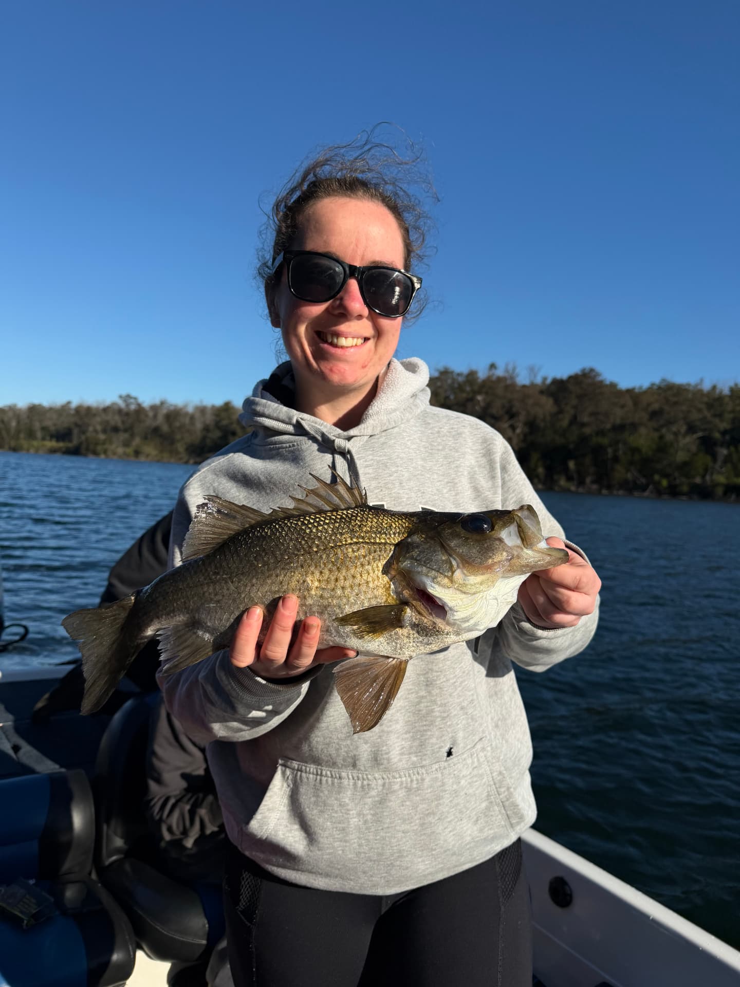 A smiling guest with an estuary perch on a clear blue day