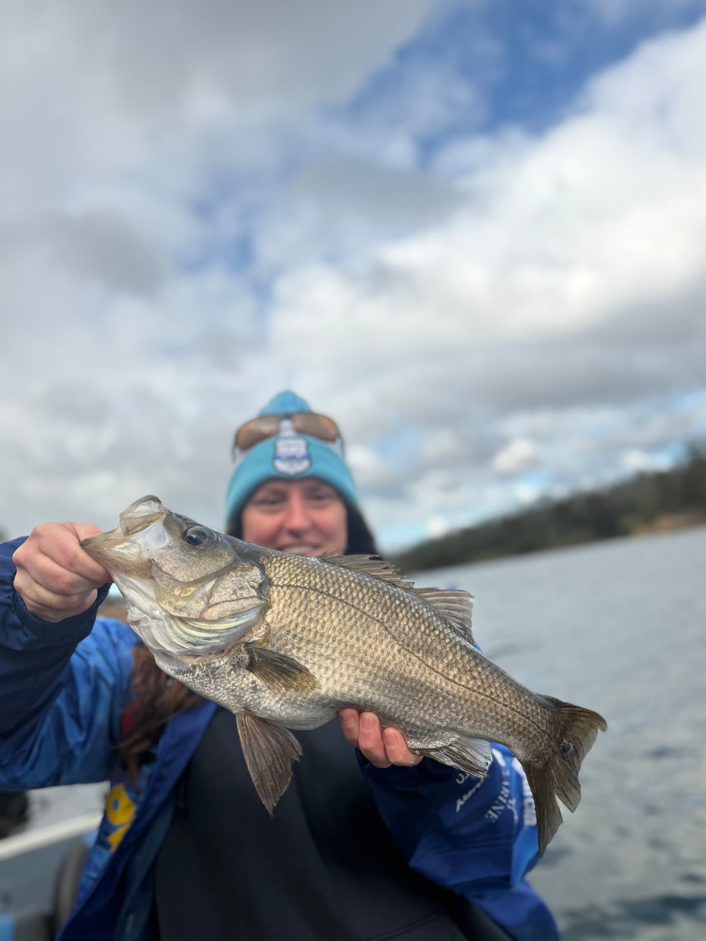 A guest holding up a big estuary perch on a cloudy day